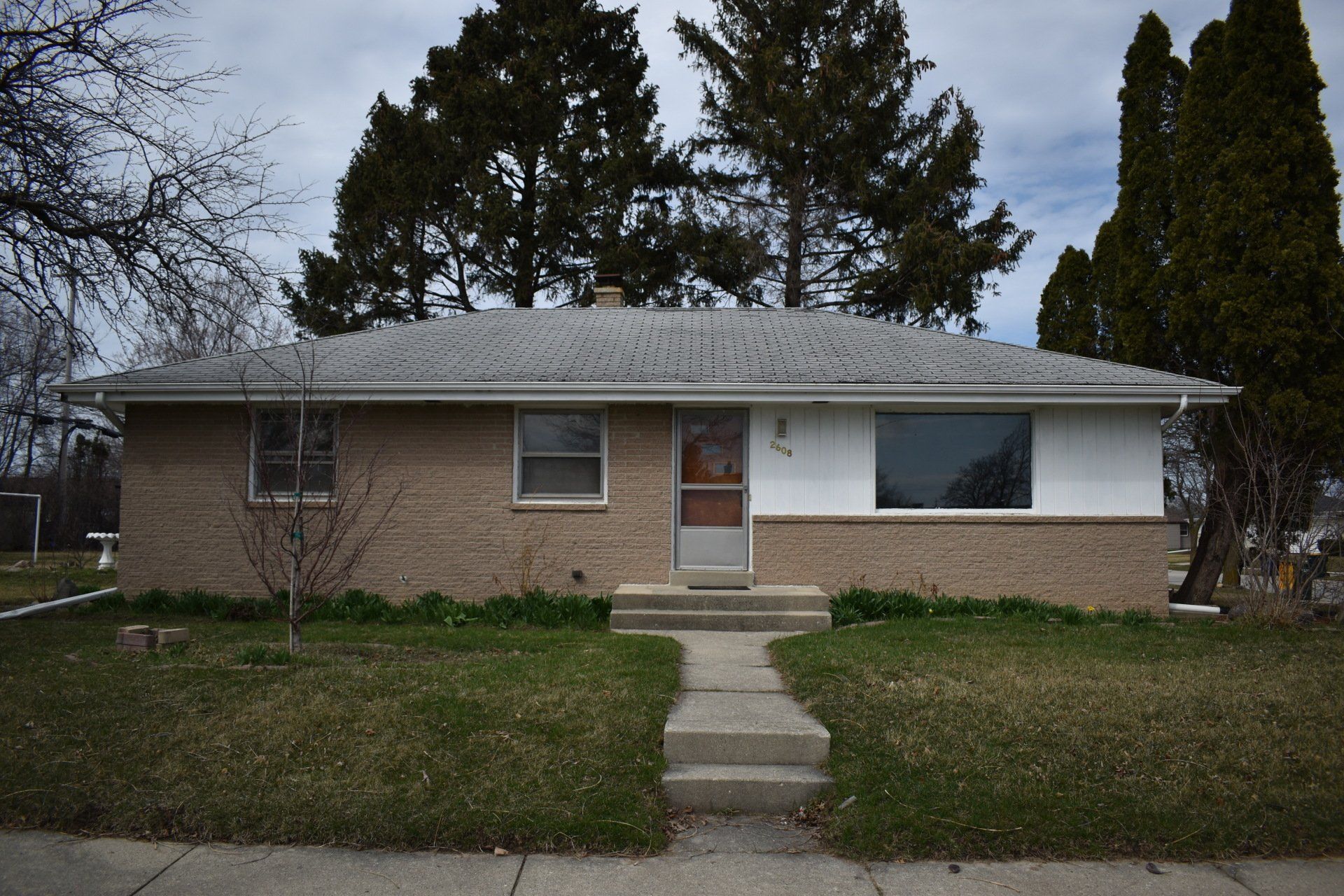 A brick house with a white trim and a gray roof