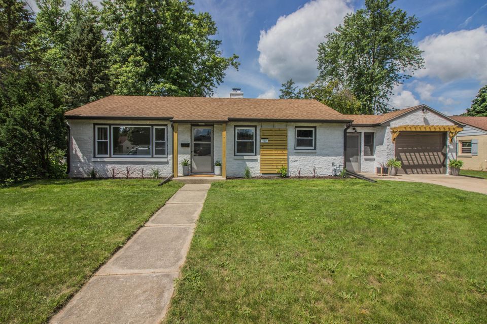A white house with a brown roof is for sale