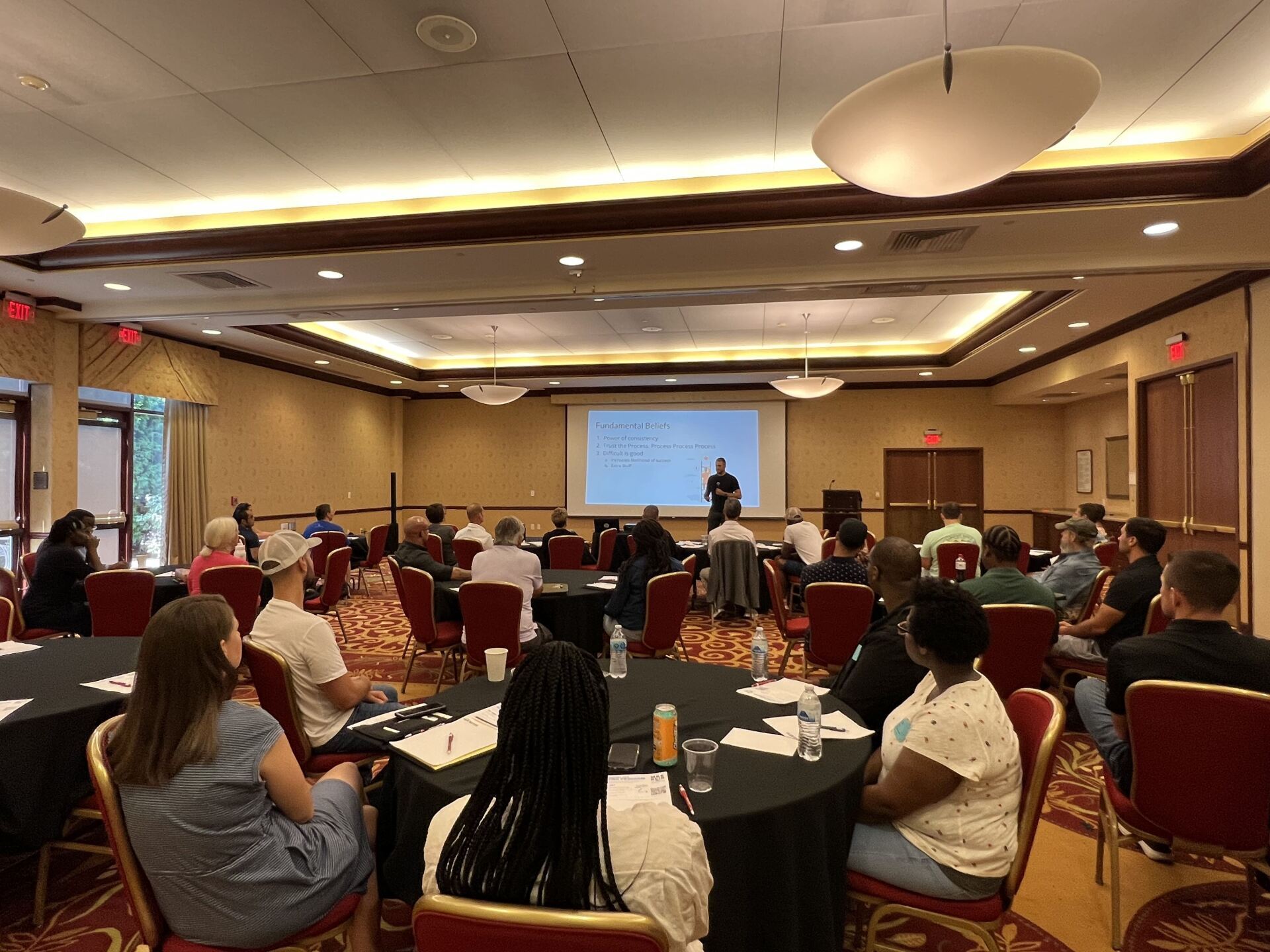 A group of people are sitting at tables in a large room.