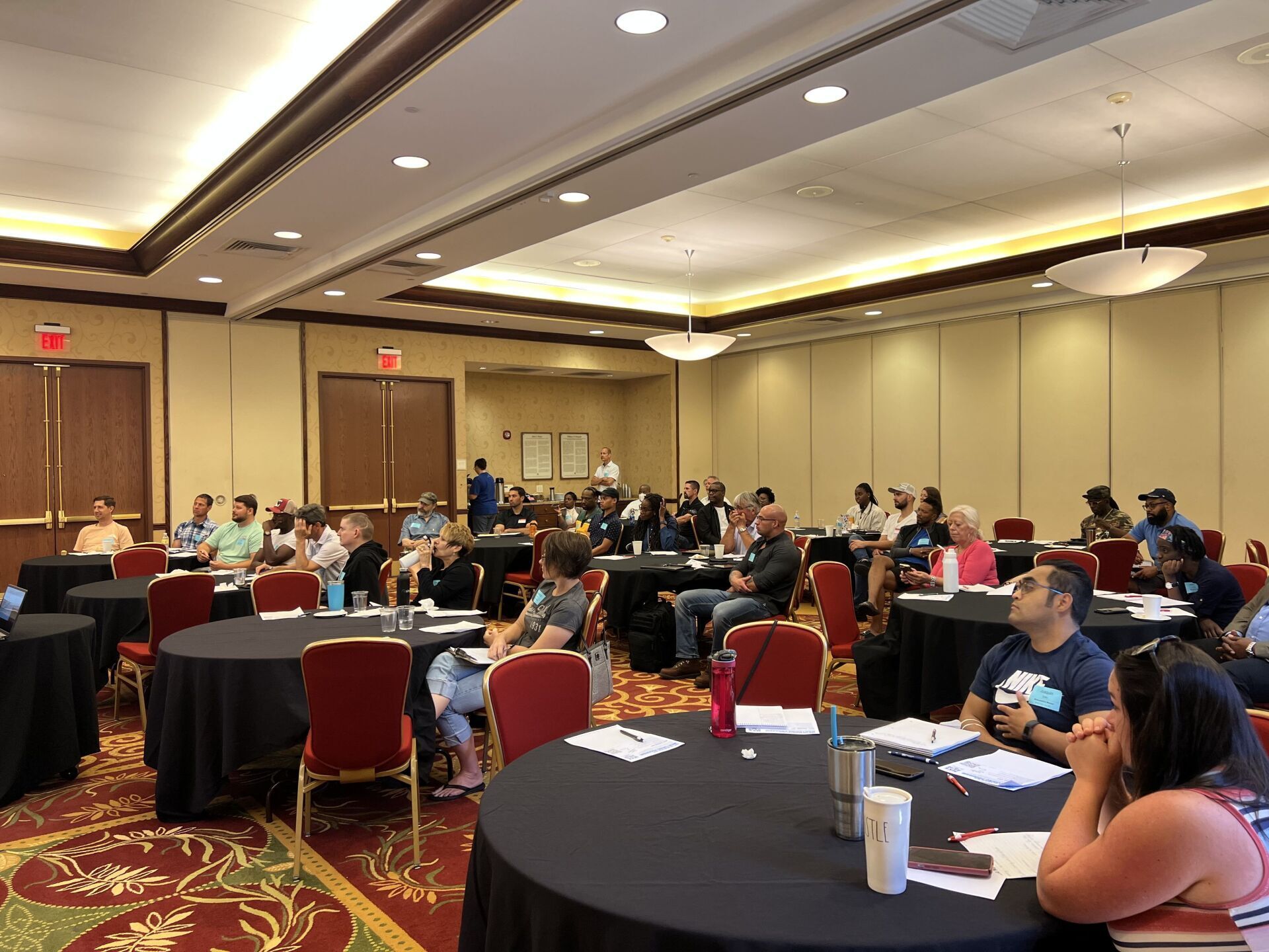 A group of people are sitting at tables in a large room.
