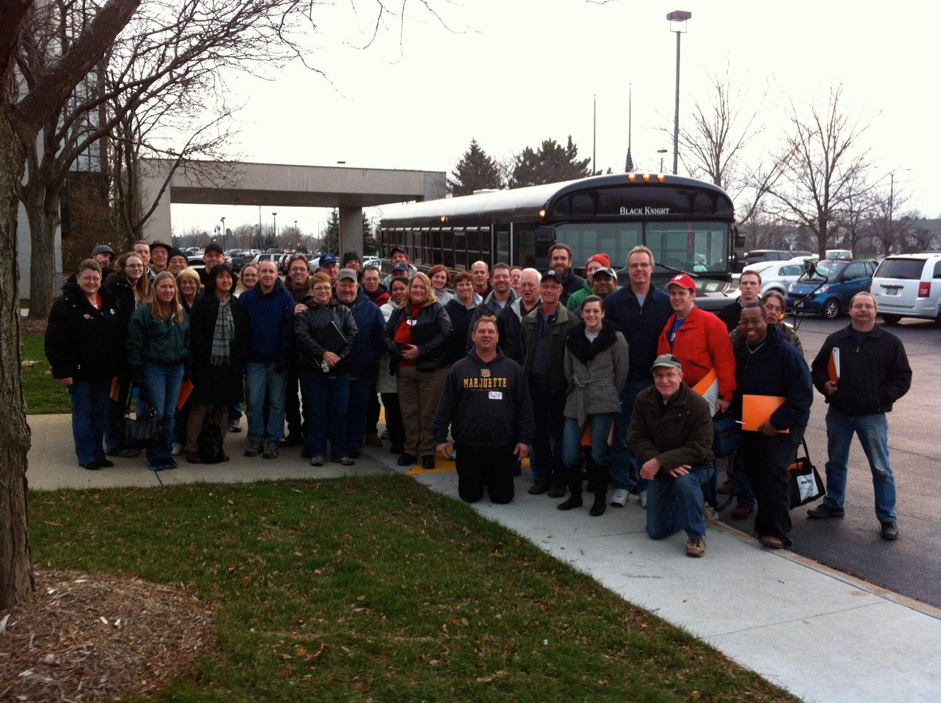 A large group of people are posing for a picture in front of a bus that says ' falcons ' on it
