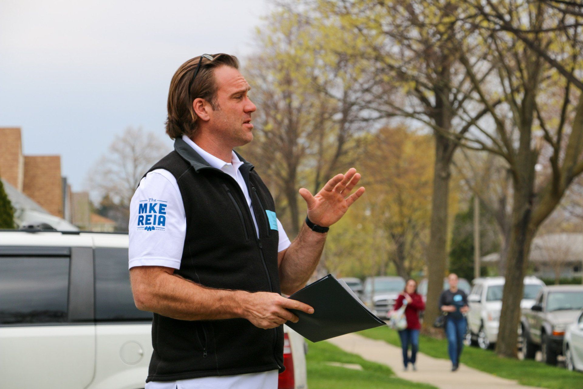 A man is standing on a sidewalk holding a clipboard.