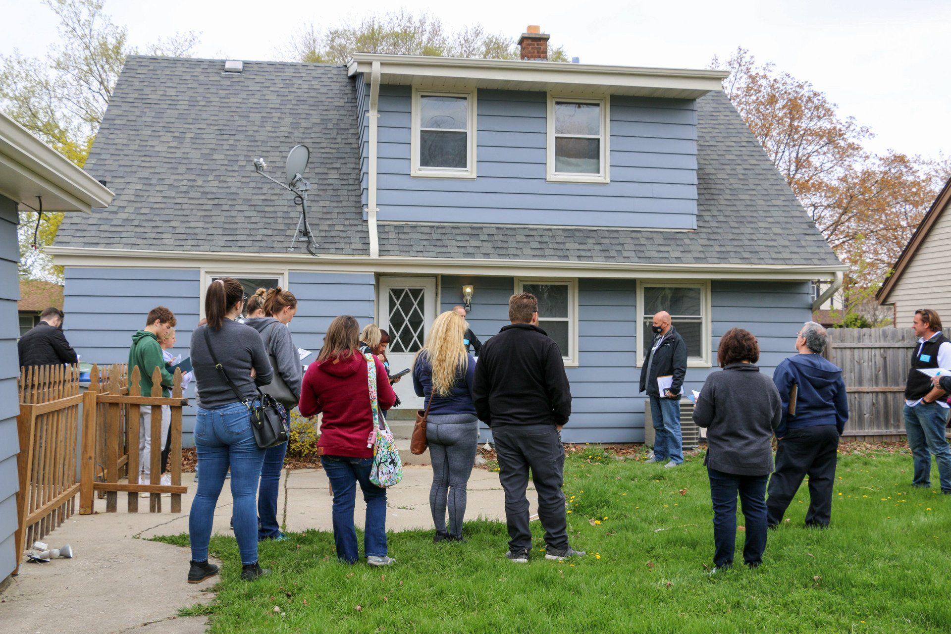 A group of people are standing in front of a blue house