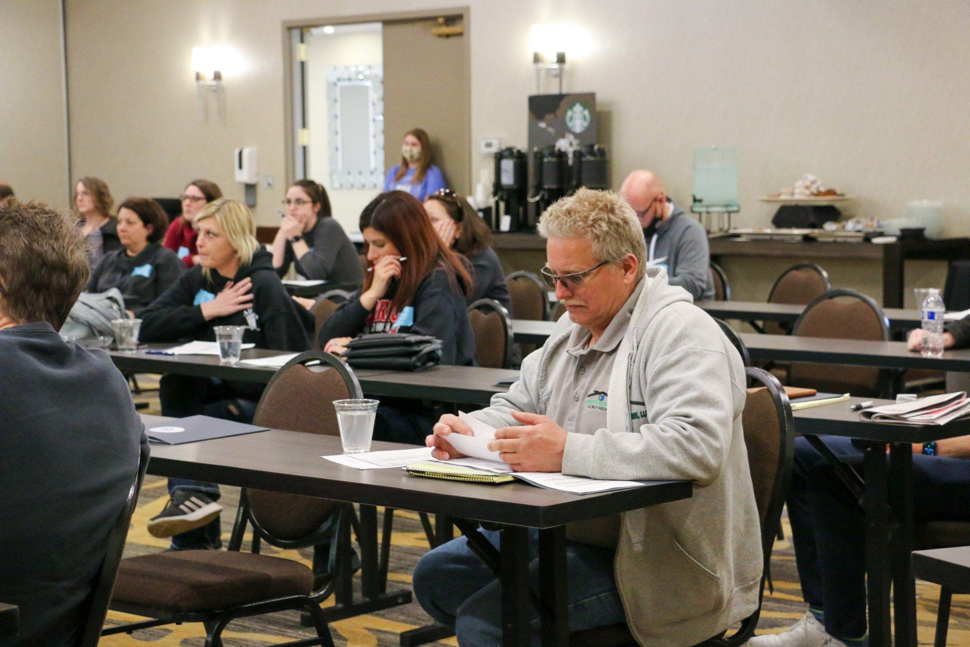 A group of people are sitting at tables in a conference room.