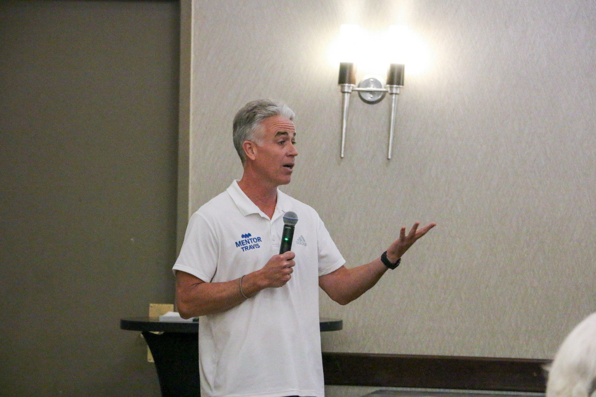 A man in a white shirt is holding a microphone in a room.