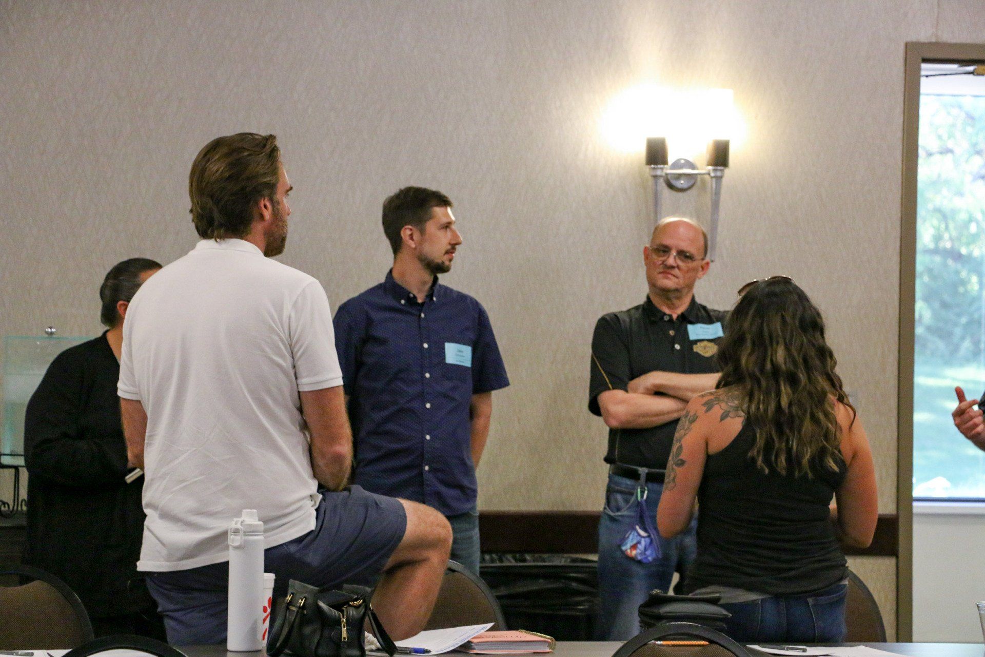 A group of people are standing around a table talking to each other.
