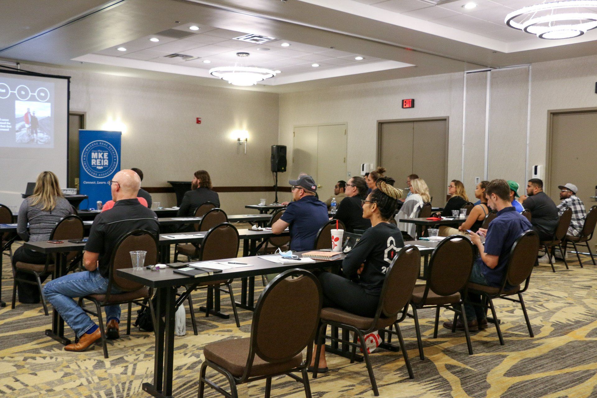 A group of people are sitting at tables in a conference room.