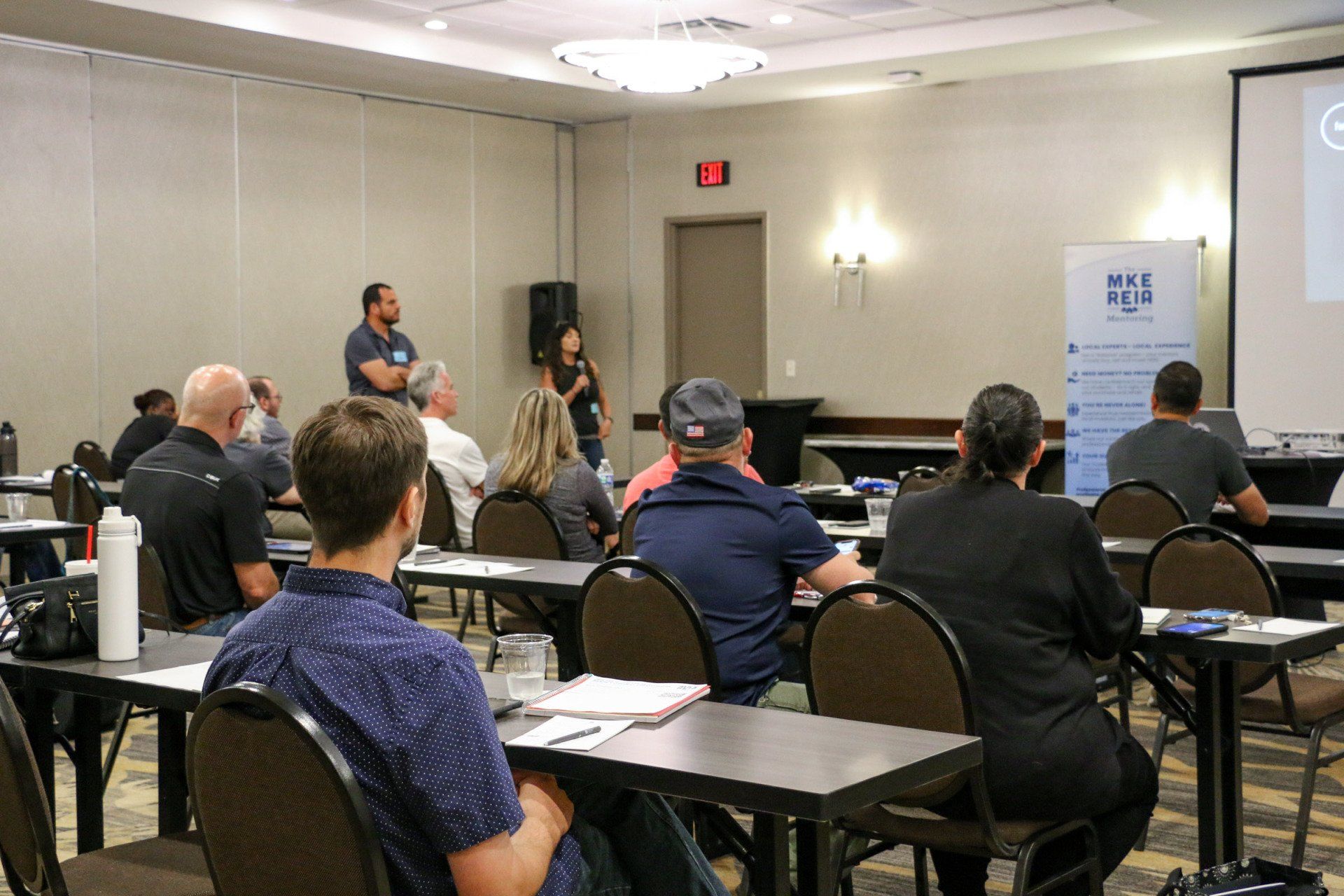A group of people are sitting at tables in a conference room.