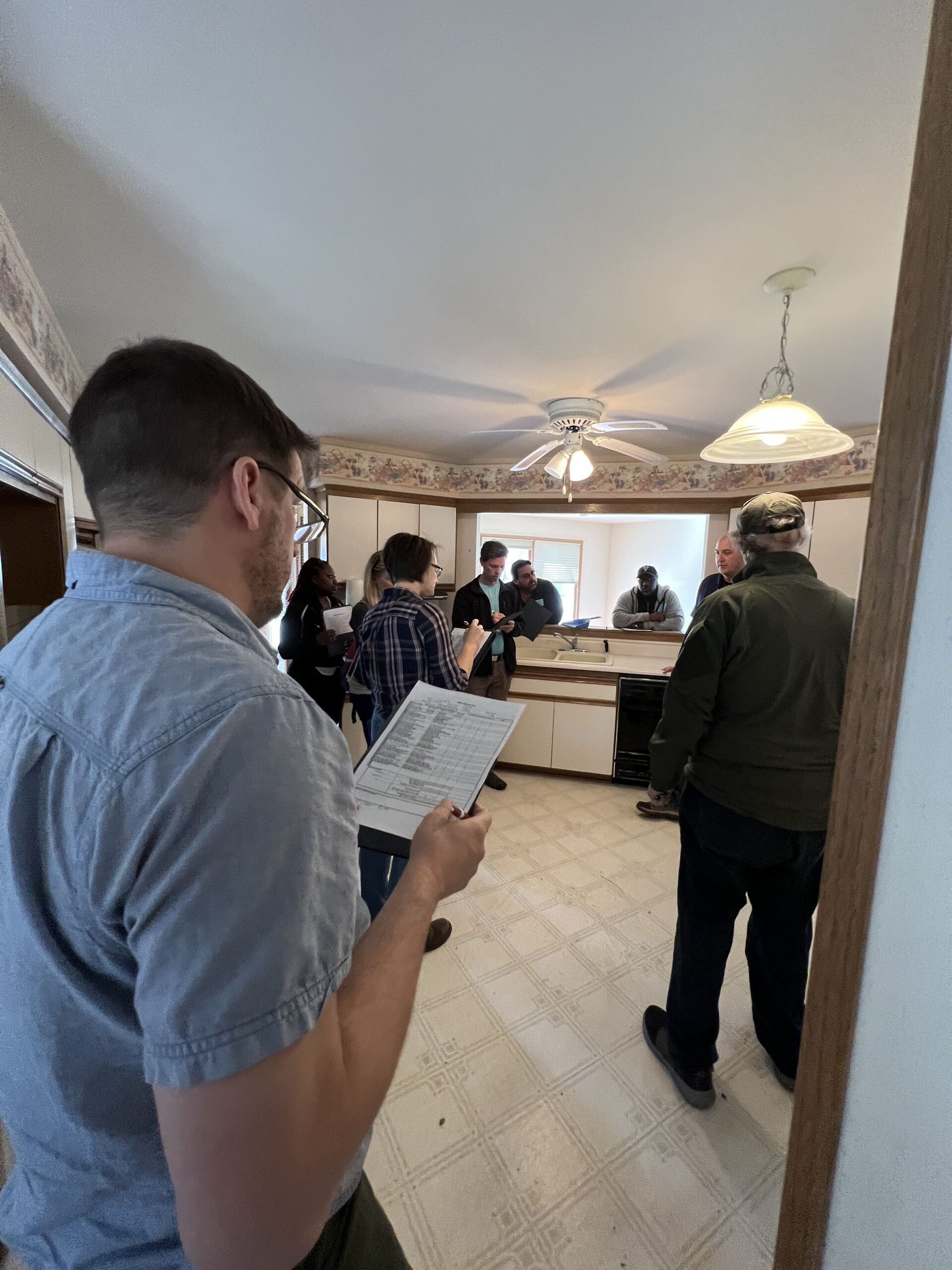 A man is standing in a kitchen holding a piece of paper.