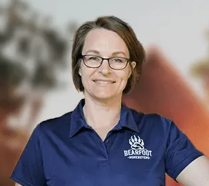 A woman wearing glasses and a blue shirt is smiling for the camera.