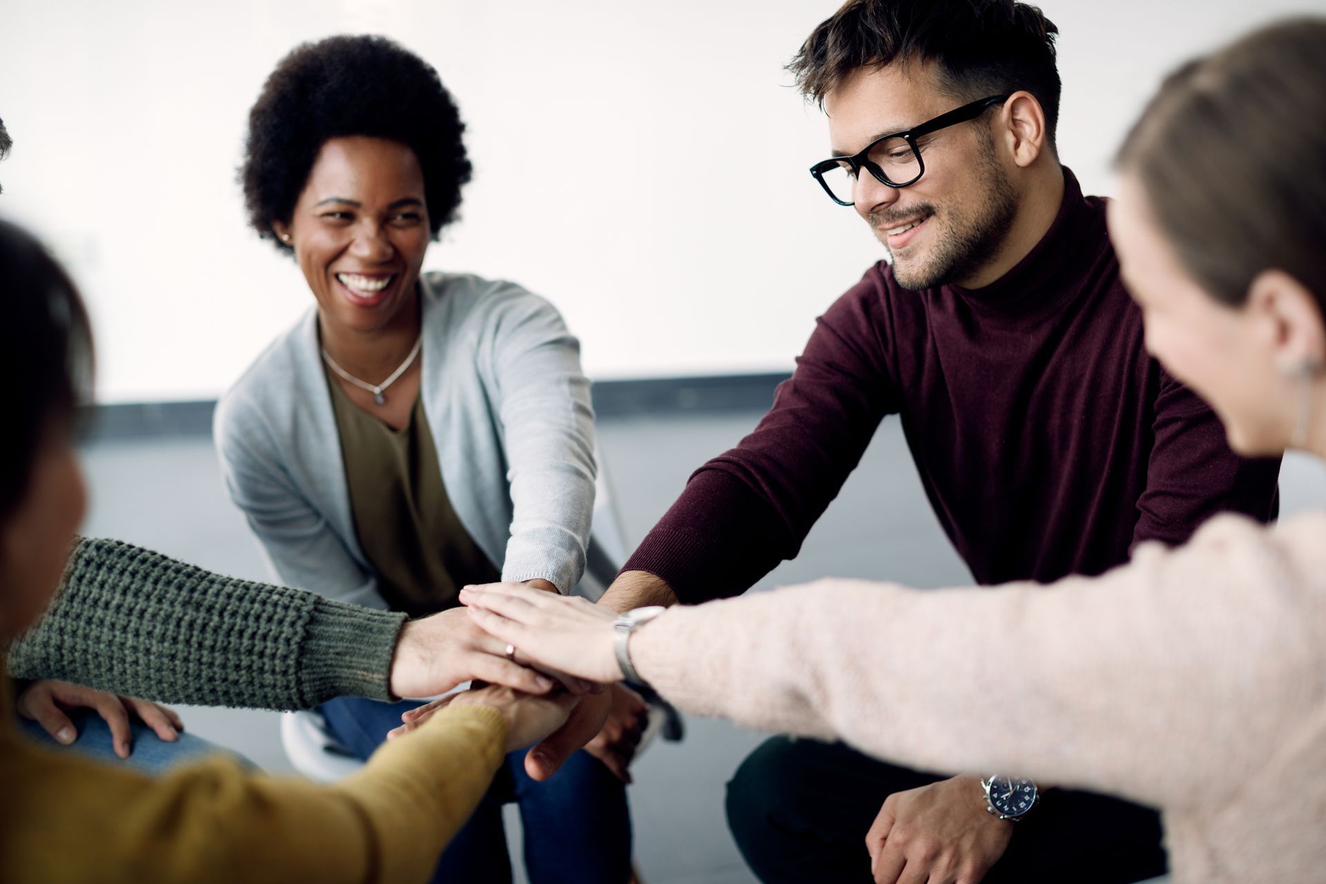 A group of business professionals in a circle displaying teamwork with a team cheer.