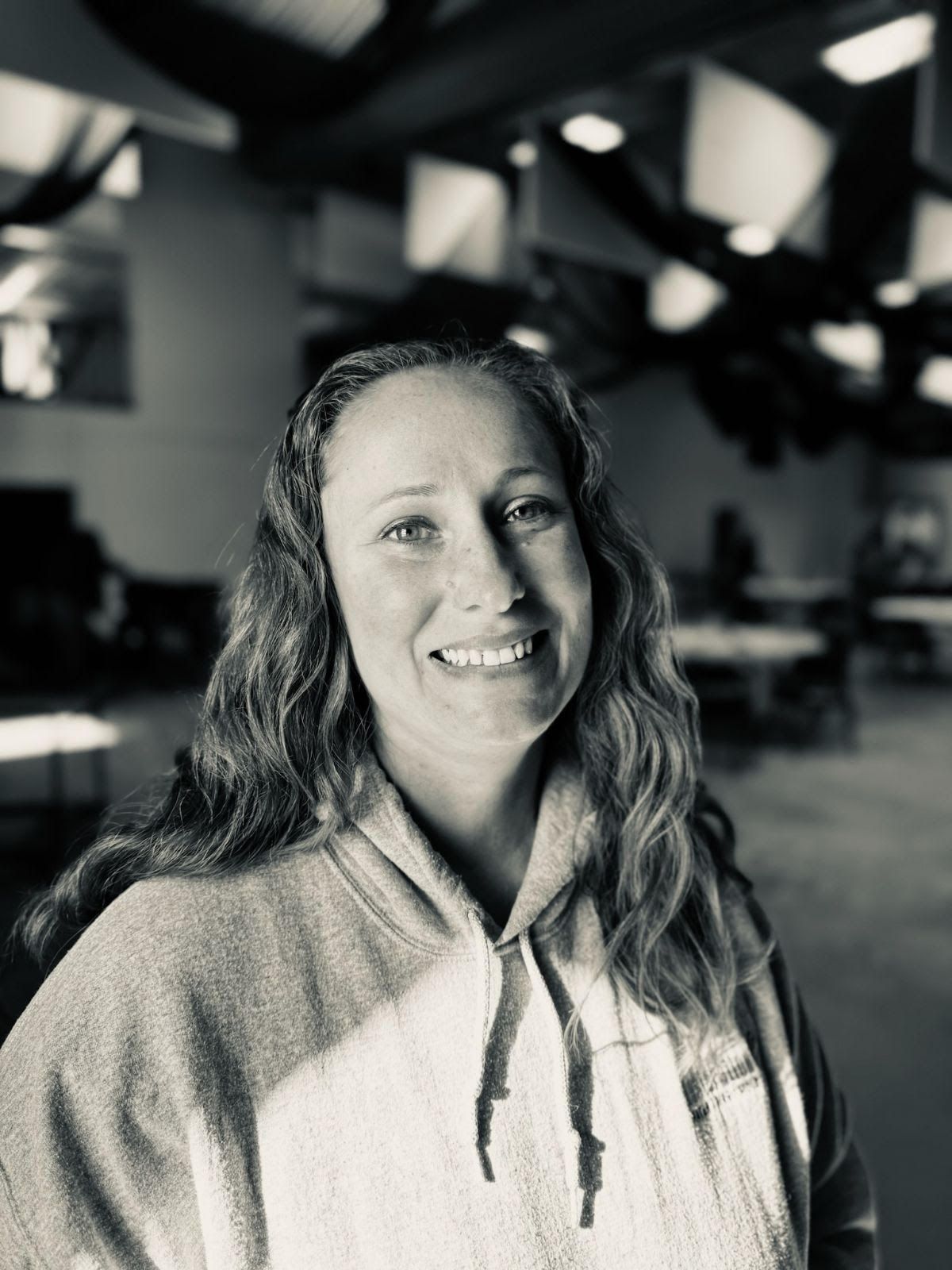 Woman with brown hair smiles, wearing a black blazer.