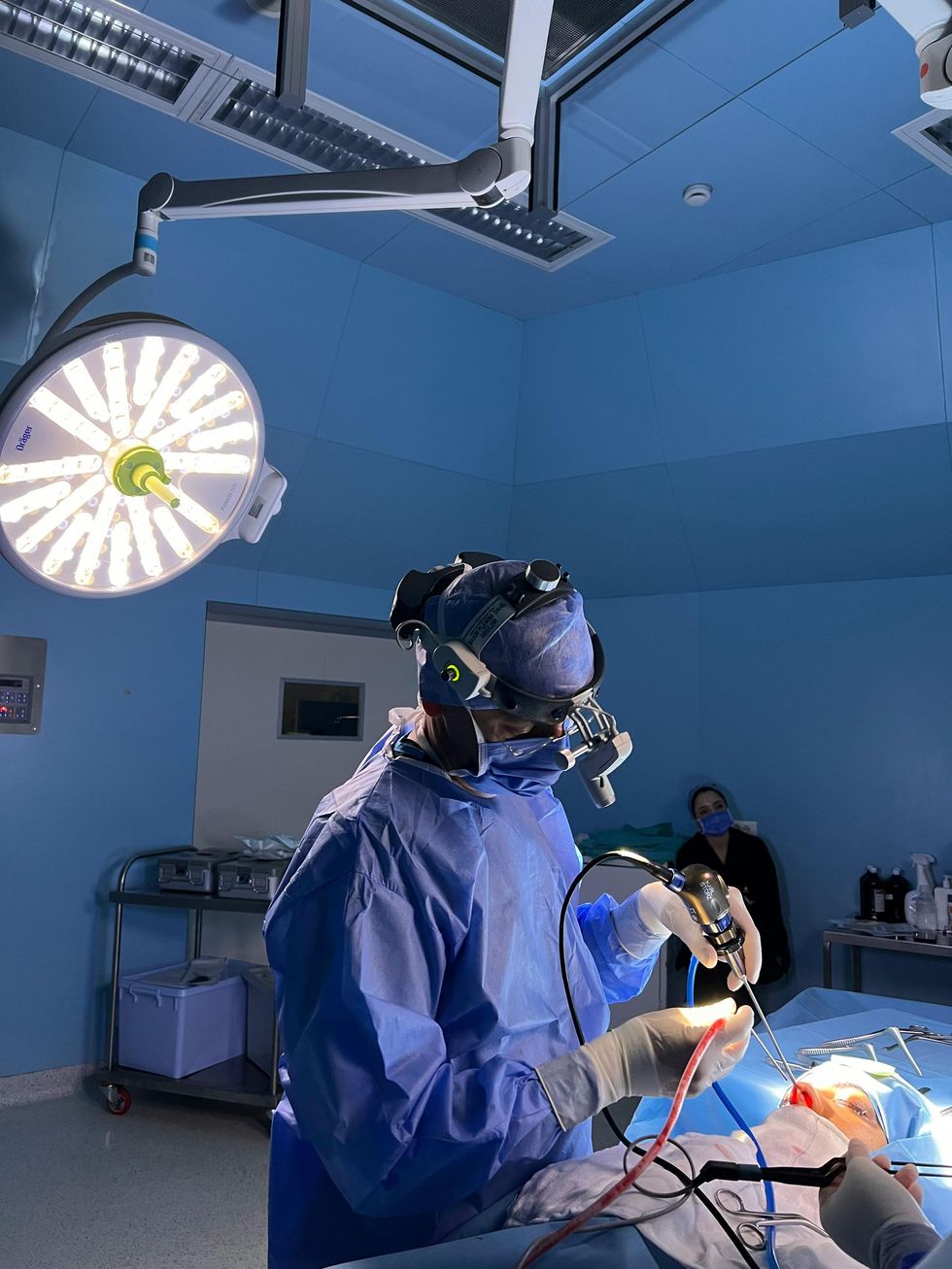 A surgeon is operating on a patient in an operating room.