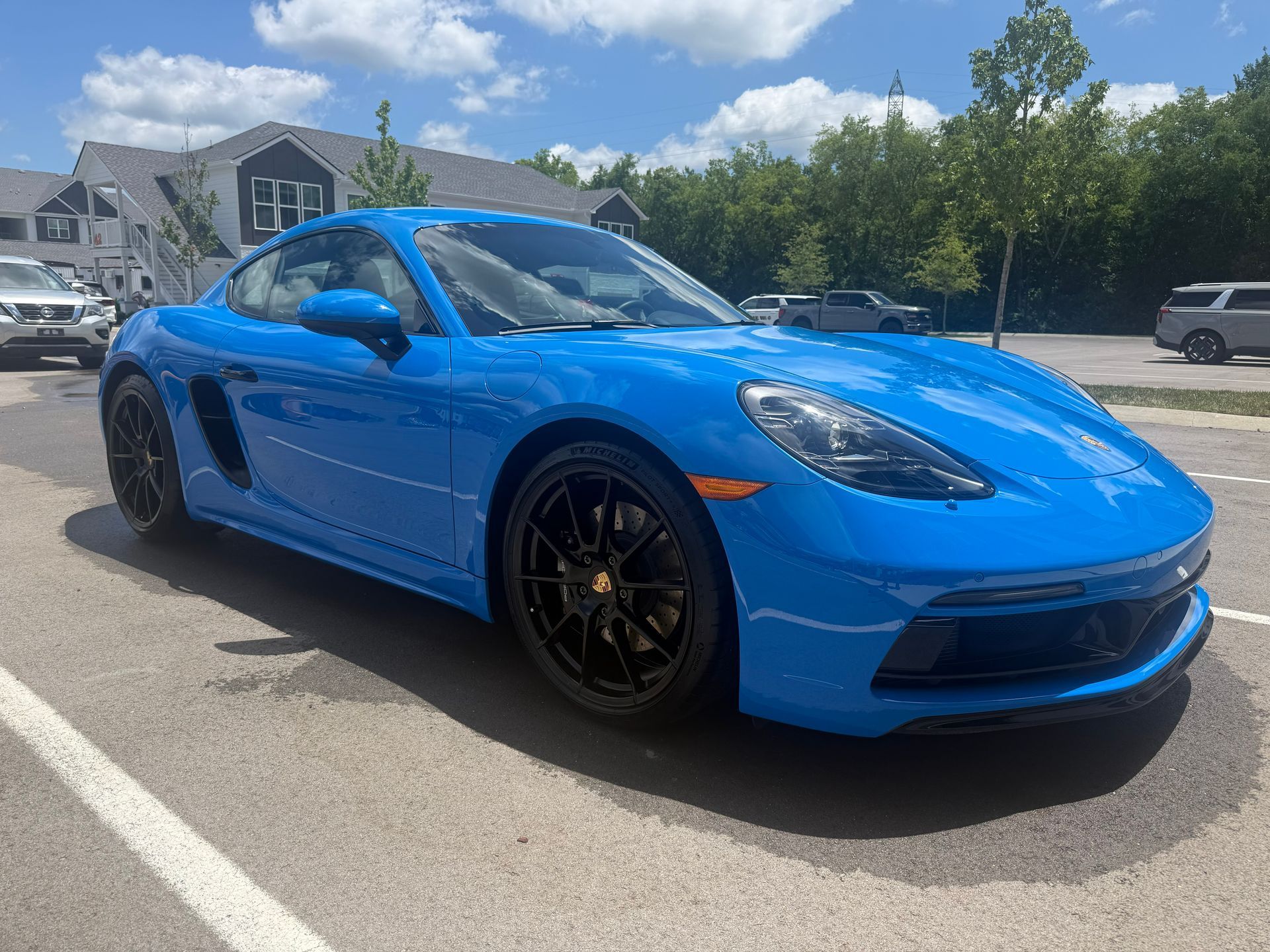 Bright blue sports car parked outdoors on a sunny street, angled front-left view
