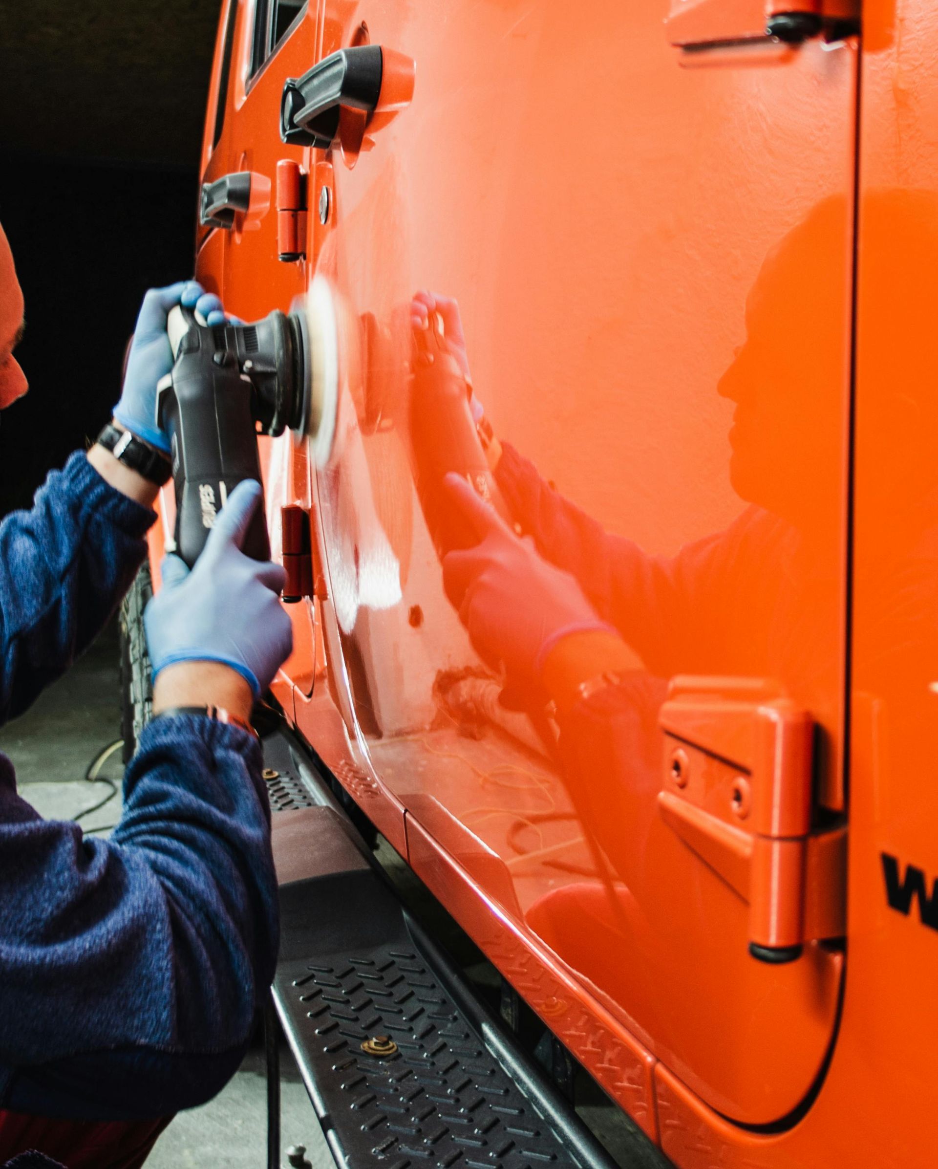 Hand polishing a gray car with a cloth and electric buffer