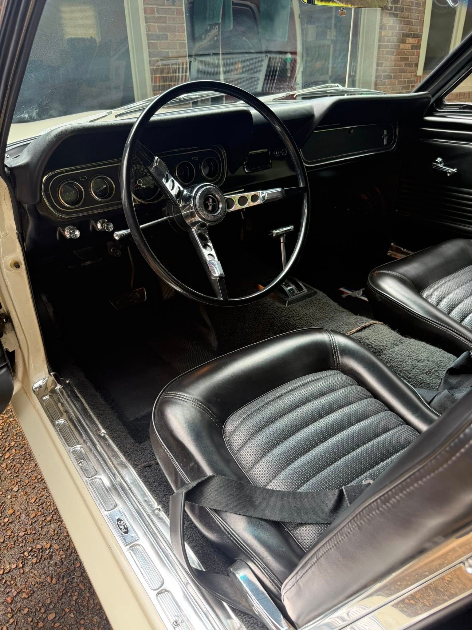 Classic car interior with black leather seats, wood-rim steering wheel, and chrome dashboard details