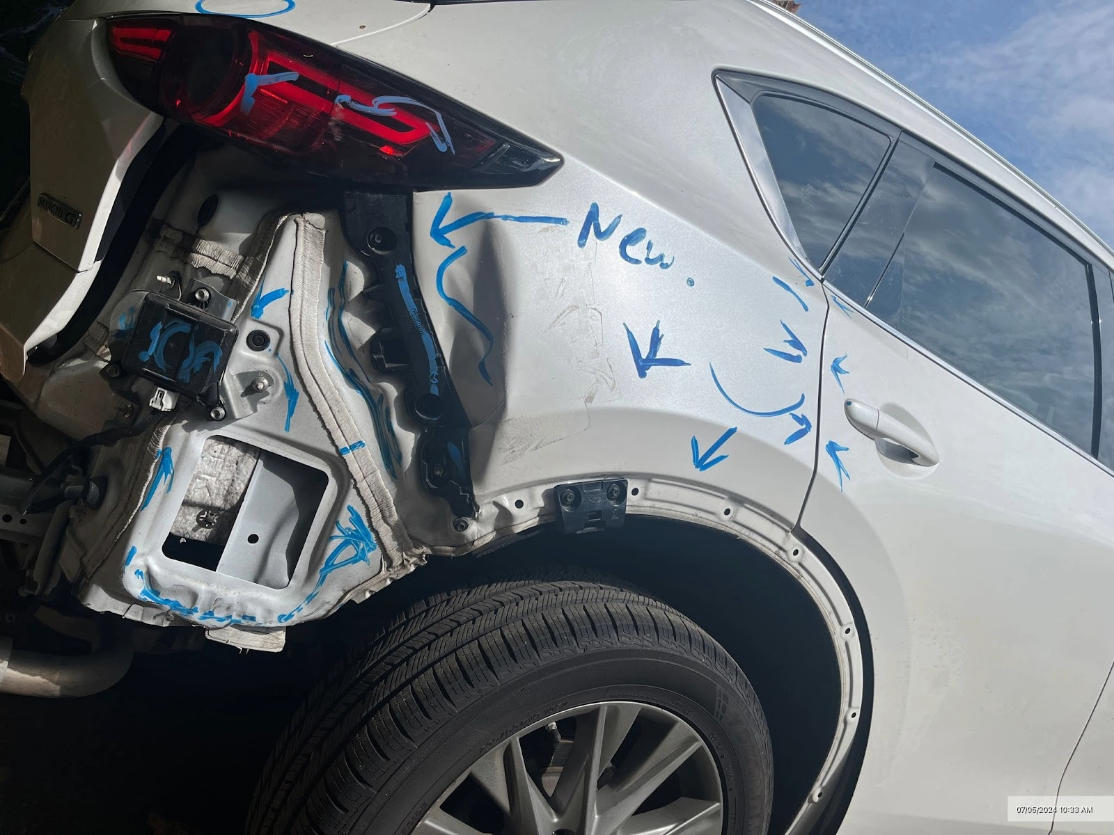 Damaged white car rear quarter panel. Blue arrows indicate areas of damage and replacement needed.