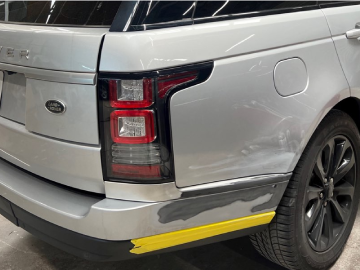 a silver range rover with a yellow stripe on the side is sitting in a garage .