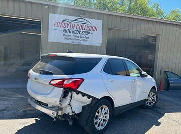 a white car is parked in front of a forsyth collision auto body shop .