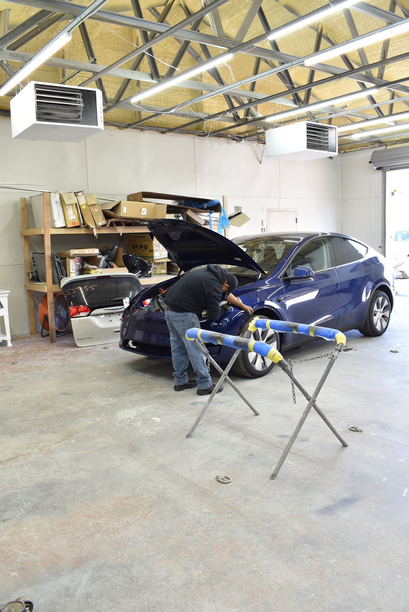 a man is working on a blue car in a garage   at Forsyth Collision in Cumming GA
