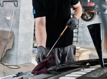 A man is checking the oil level of a car in a garage.