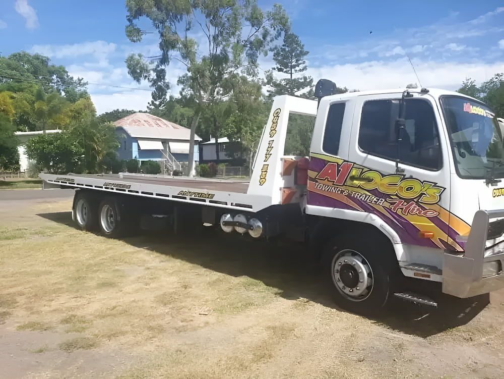A Tow Truck With A Flat Bed Is Parked In A Grassy Field — A1 Loco's Towing In West Rockhampton, QLD