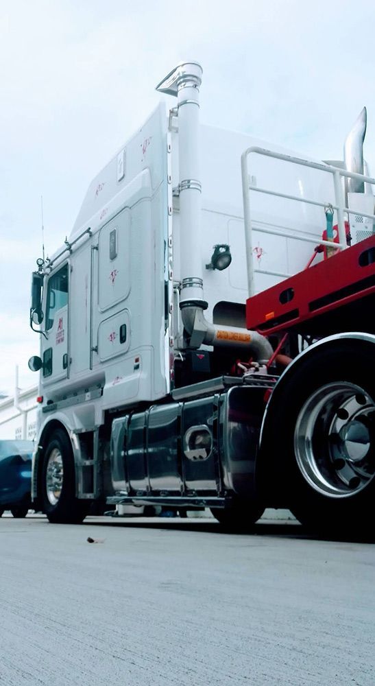 White Semi-truck With Red Trailer Parked Outdoors on a Cloudy Day — A1 Loco's Towing in Gladstone, QLD
