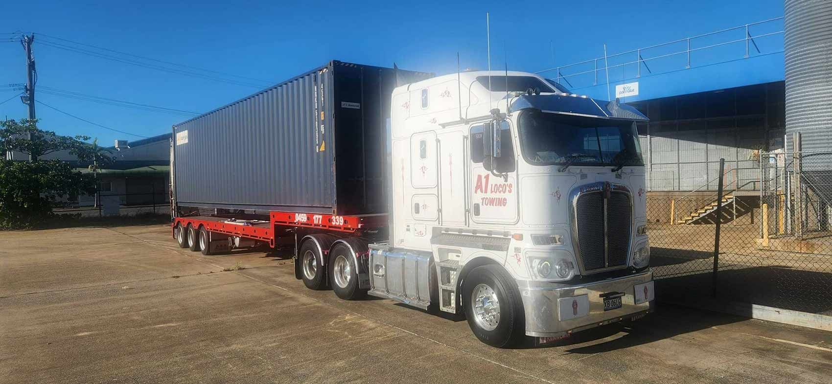 A White Semi-truck With a Blue Container Parked on a Gravel Lot — A1 Loco's Towing in Emerald, QLD