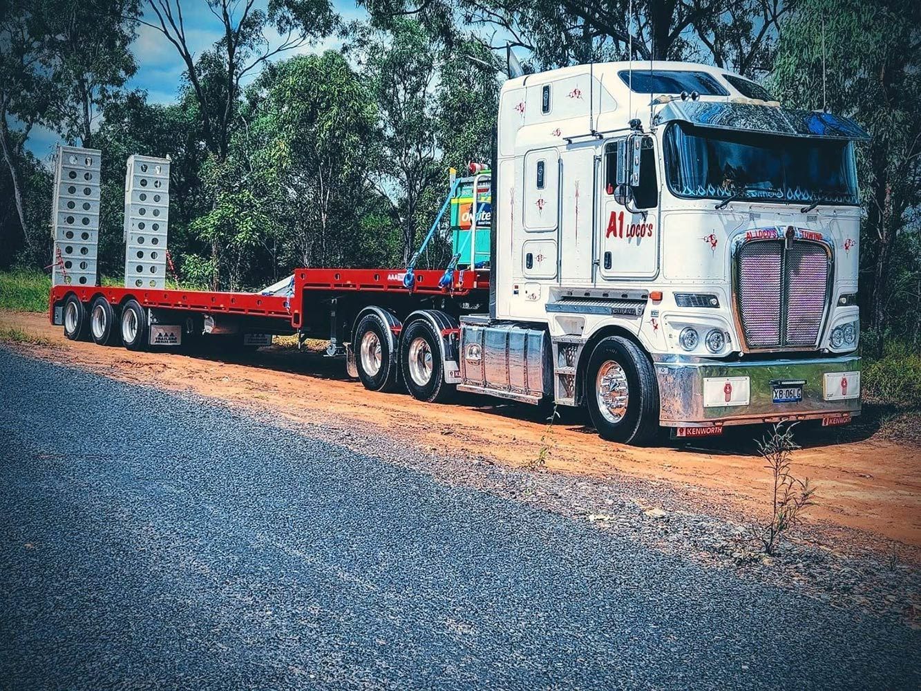 White Semi-truck With Red Trailer on a Gravel Road in Front of Trees — A1 Loco's Towing in Blackwater, QLD
