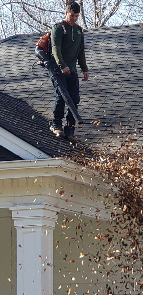 A man is cleaning a wooden deck with a high pressure washer.