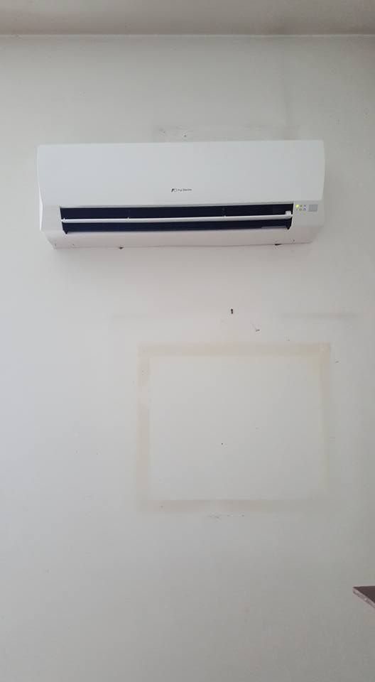 Condizionatore d'aria bianco montato su una parete bianca; macchia chiara sotto.