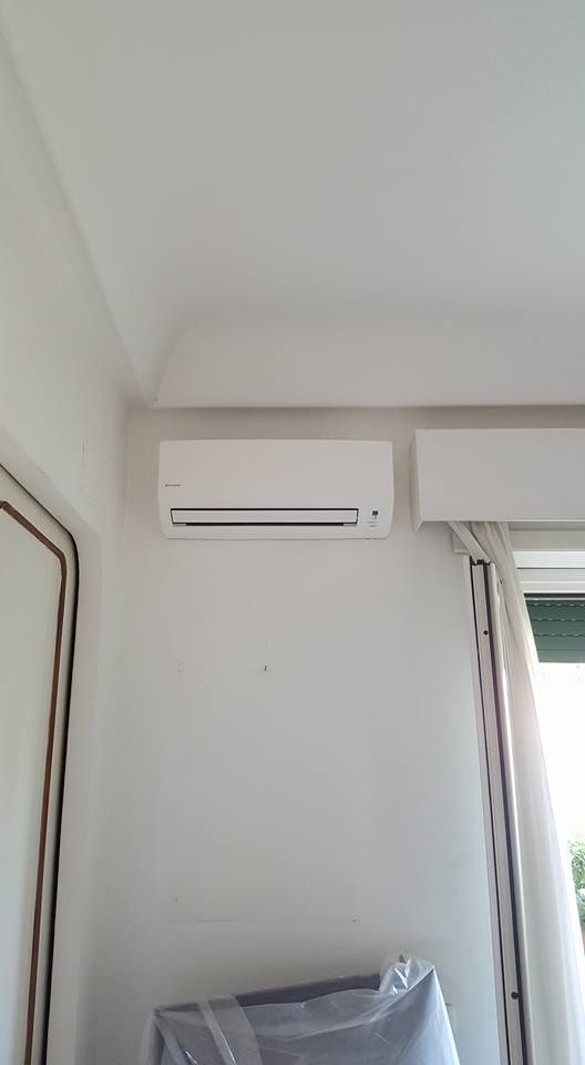 Condizionatore d'aria bianco montato su una parete bianca in una stanza.