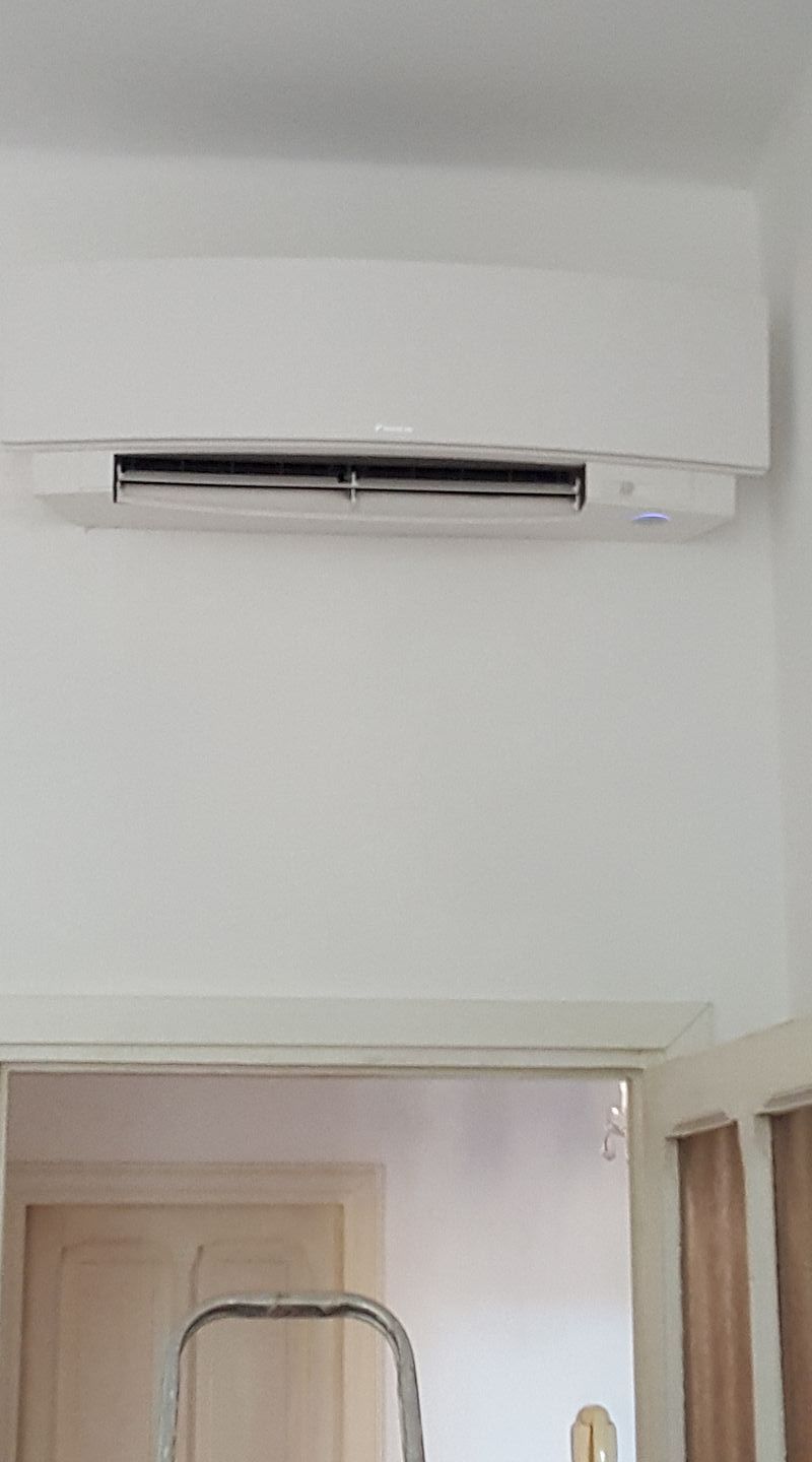 Condizionatore d'aria bianco montato su una parete bianca sopra una porta.