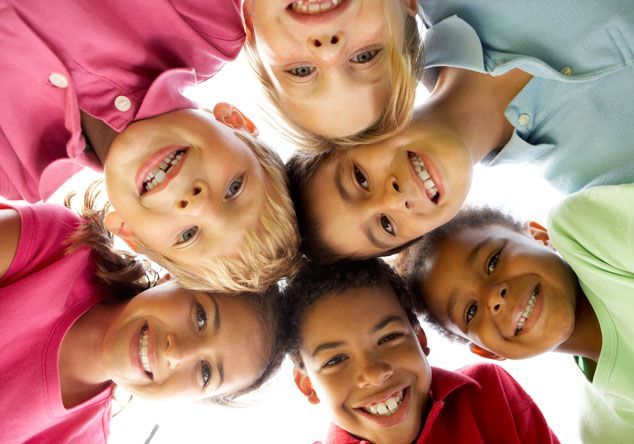 A group of children are standing in a circle and smiling