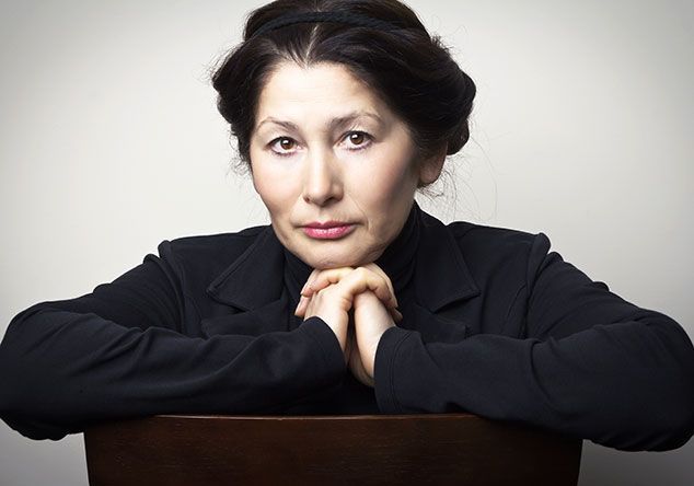 A woman is sitting in a chair with her hands folded