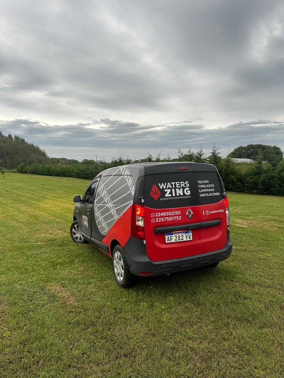 Una camioneta roja está estacionada en un campo de hierba.