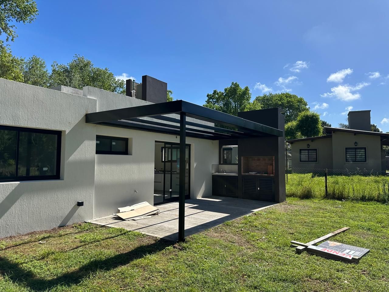 Una casa con pérgola y parrilla en el patio trasero.