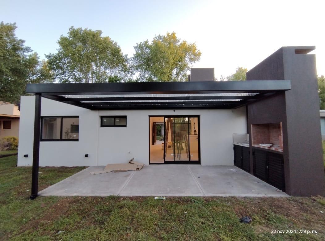 Una casa blanca con una pérgola negra y una parrilla.