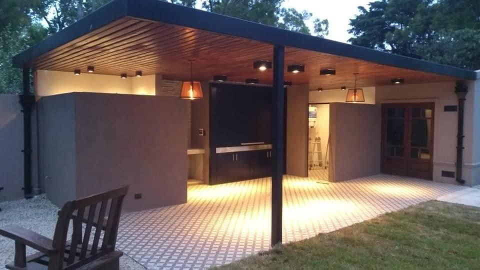 Un banco de madera se encuentra debajo de un patio cubierto frente a una casa.