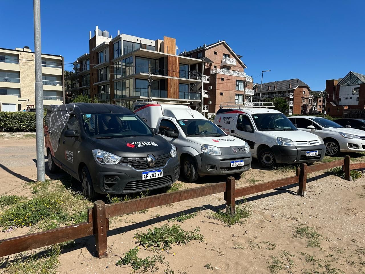 Una fila de coches están aparcados al lado de una valla de madera.