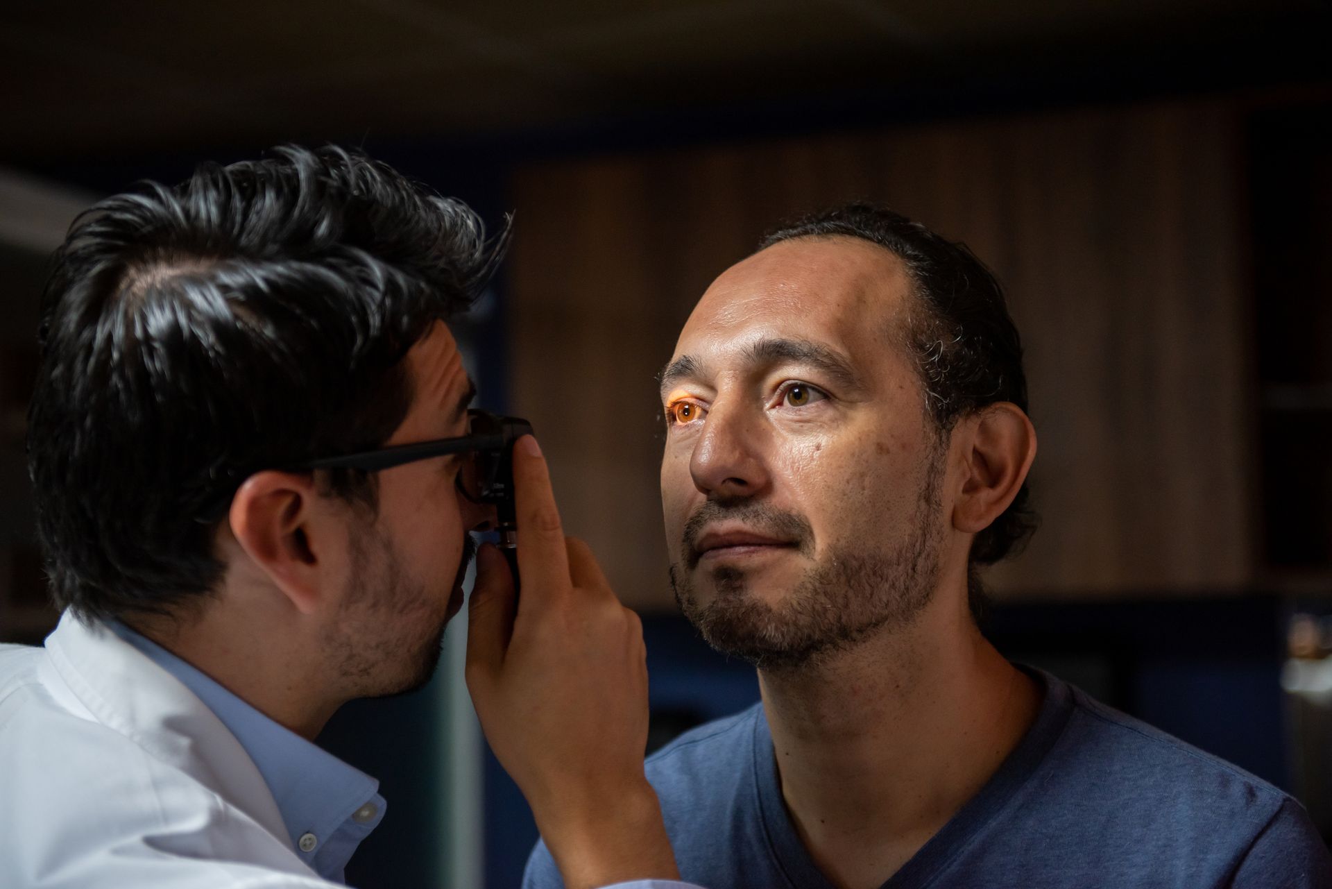 A neurosurgeon is checking the eye of a patient. A neurosurgeon is checking the eye of a patient.