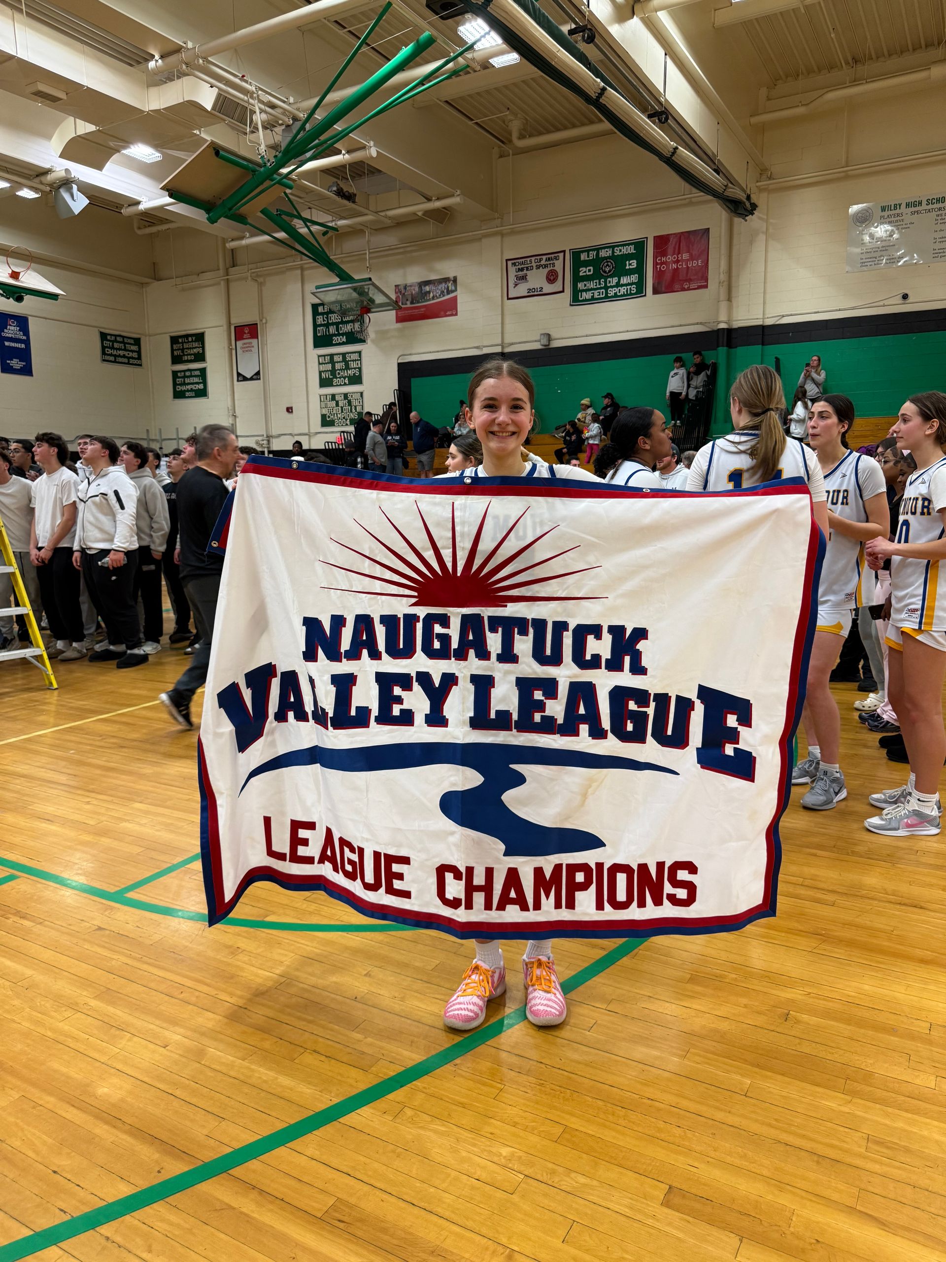 A smiling student holds a white banner that says