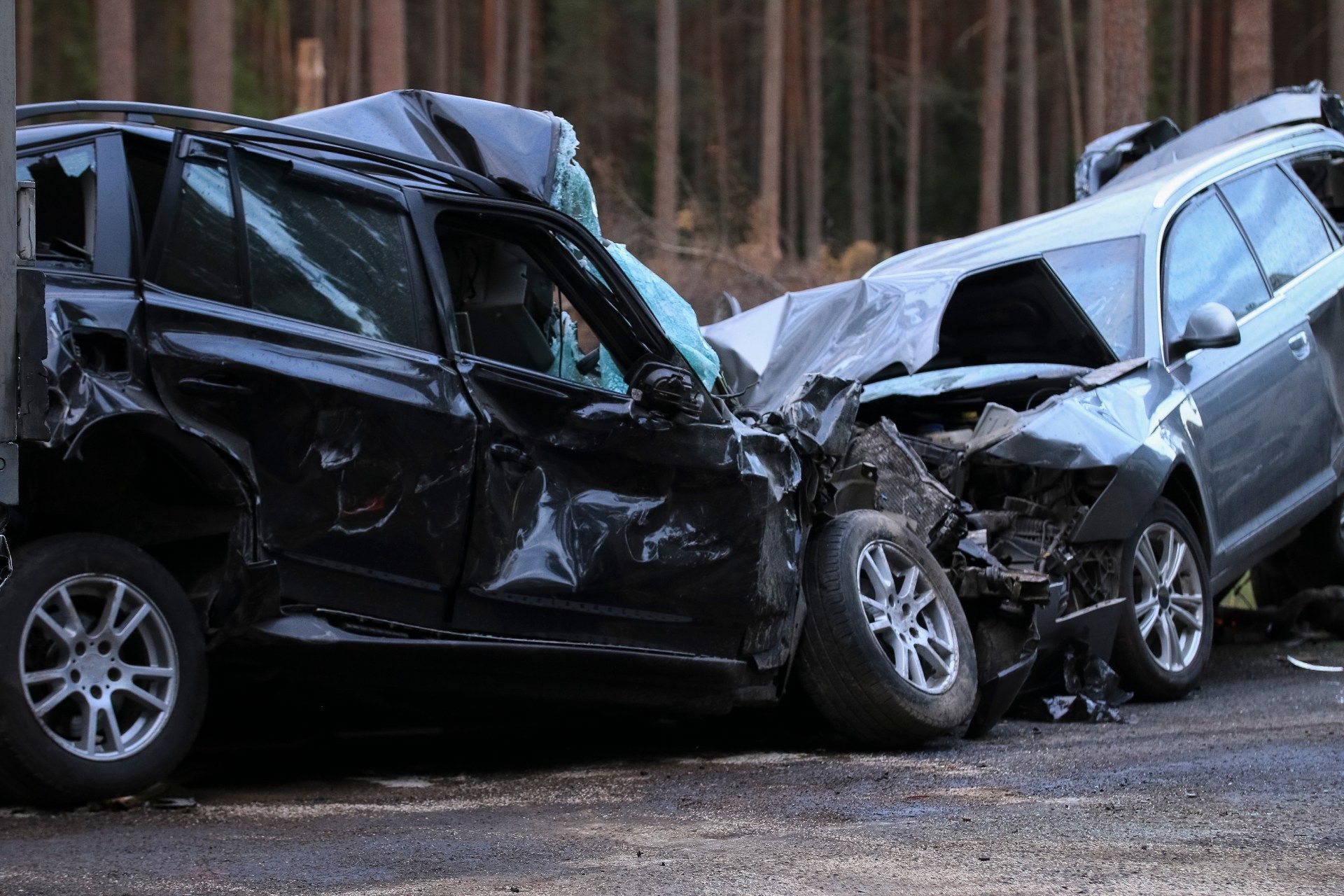 Two cars are damaged in a car accident in the woods.