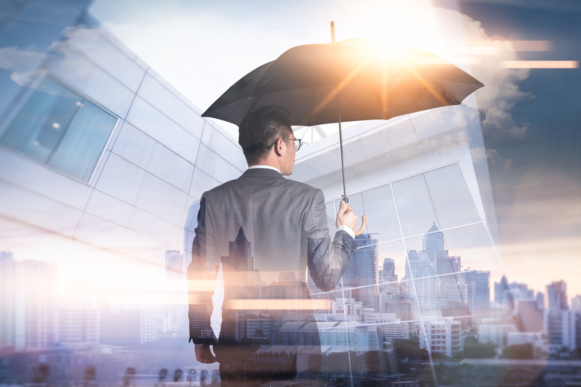 A man in a suit is holding an umbrella over a city.