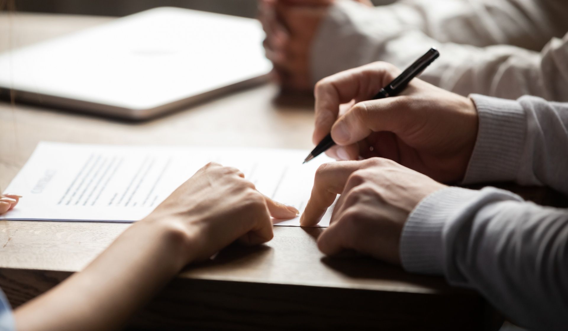 A man and a woman are signing a document at a table.