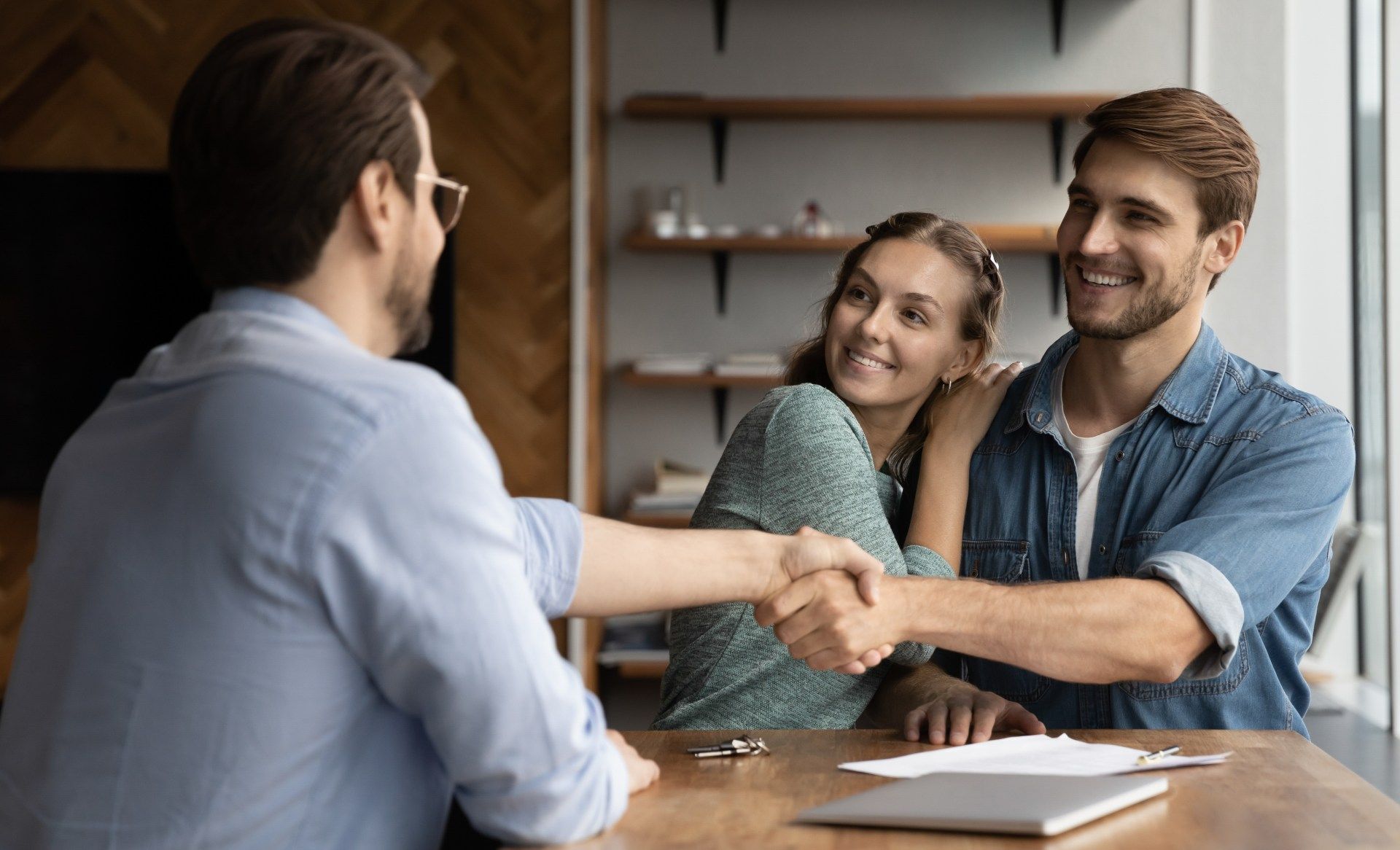 A man and woman are shaking hands with a real estate agent.