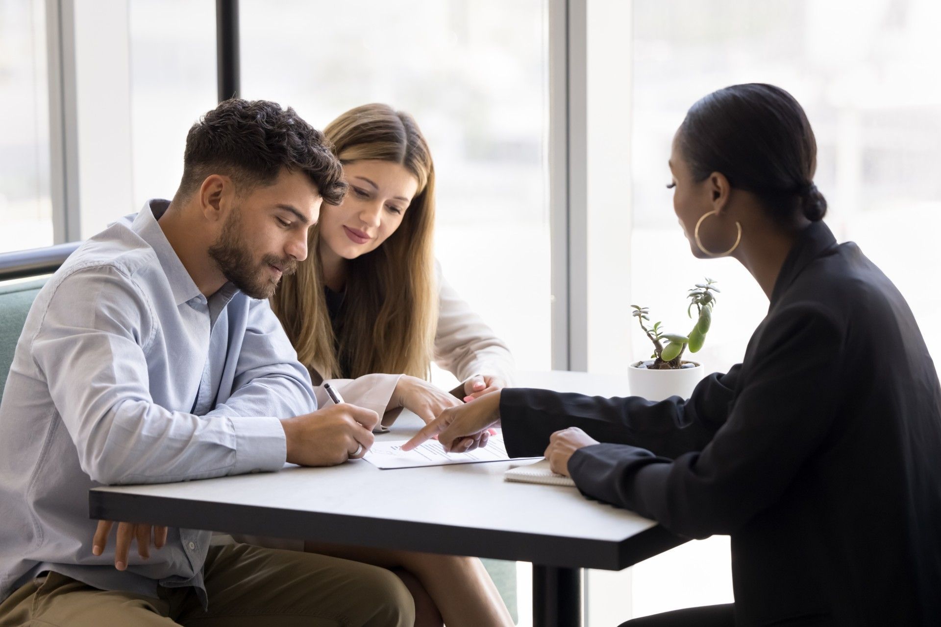 A man and a woman are sitting at a table talking to a woman.