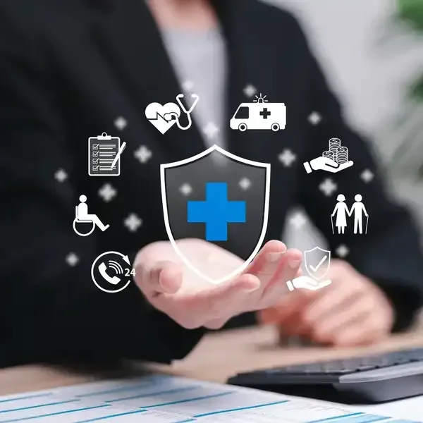 A person in a business suit holds a digital shield icon with a blue cross, surrounded by various healthcare-related symbols.