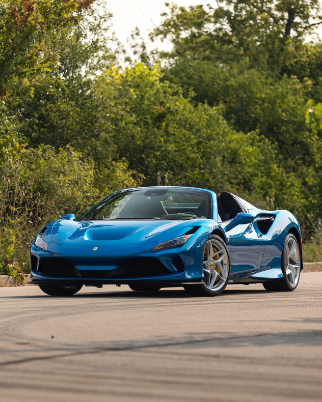 Blue sports car parked on a road with trees in the background