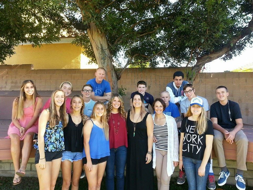 Group of teens and adults posing under a tree outdoors.